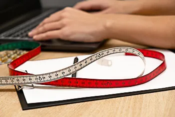 engrosamiento_de_miembro_doctor_teclado_cinta_metrica_rene_zamora_queretaro_350x233 Doctor escribe en laptop junto a cinta metrica sobre libreta, simbolizando evaluacion y planeacion de tratamiento estetico.